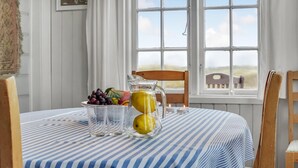 A dining table with a striped tablecloth, a pitcher of lemonade, and a bowl of fruit. - Beautiful home in Rømø with WiFi (Rømø)