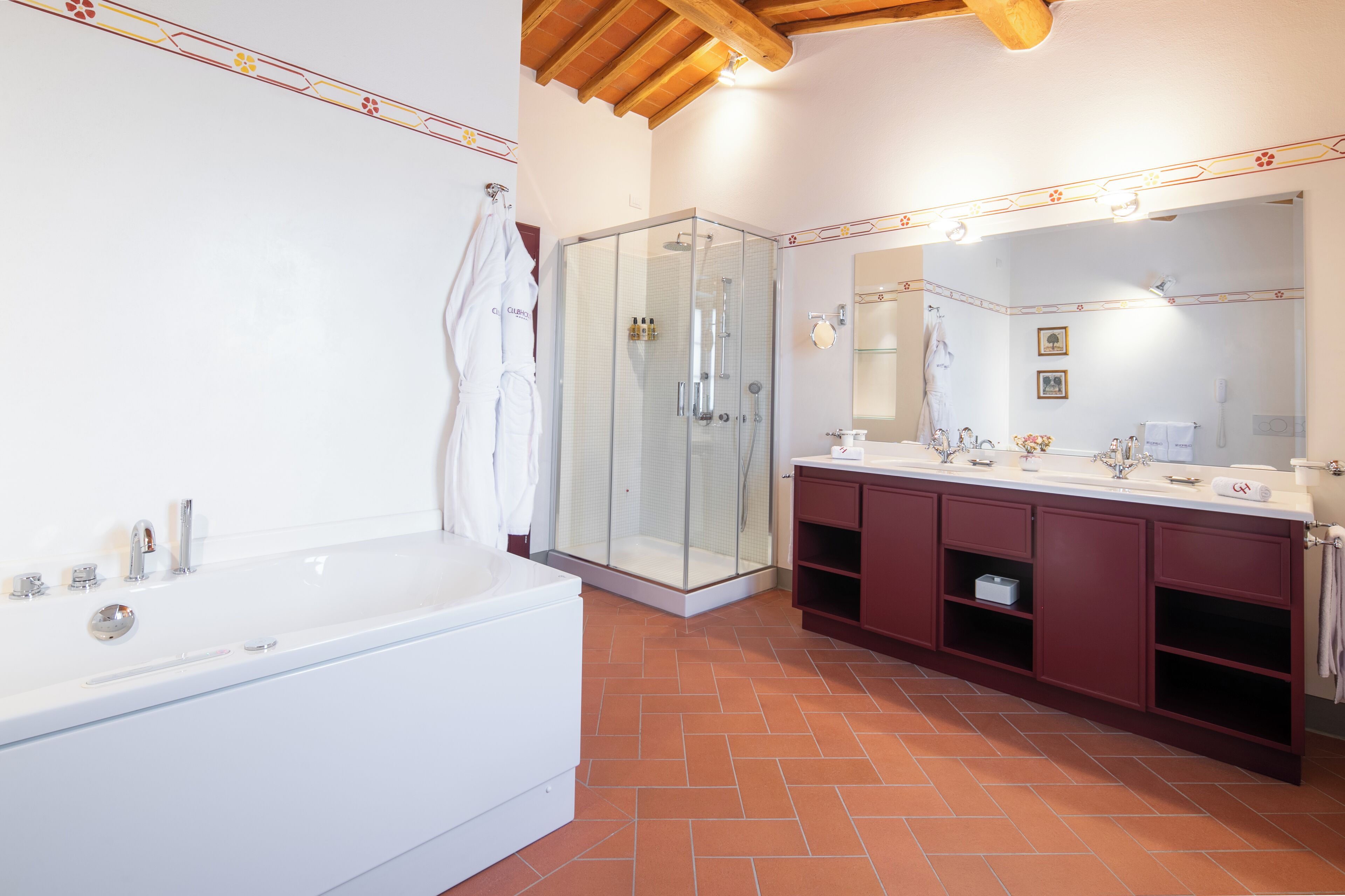 A modern bathroom with a glass-enclosed shower, a large white bathtub, and a vanity with a mirror.