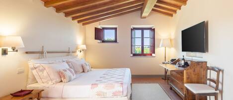 A bedroom with a bed, bedside tables, a dresser, a TV, and two windows.