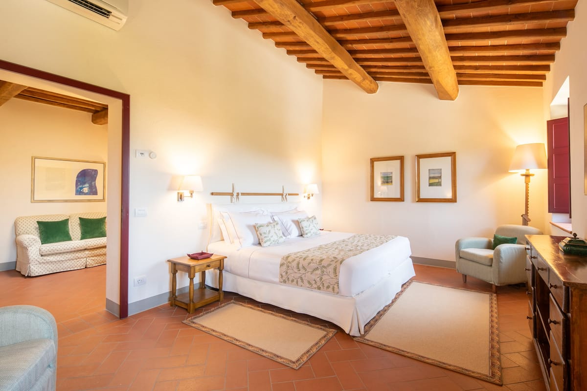 A bedroom with a bed, bedside tables, a sofa, and a chair.