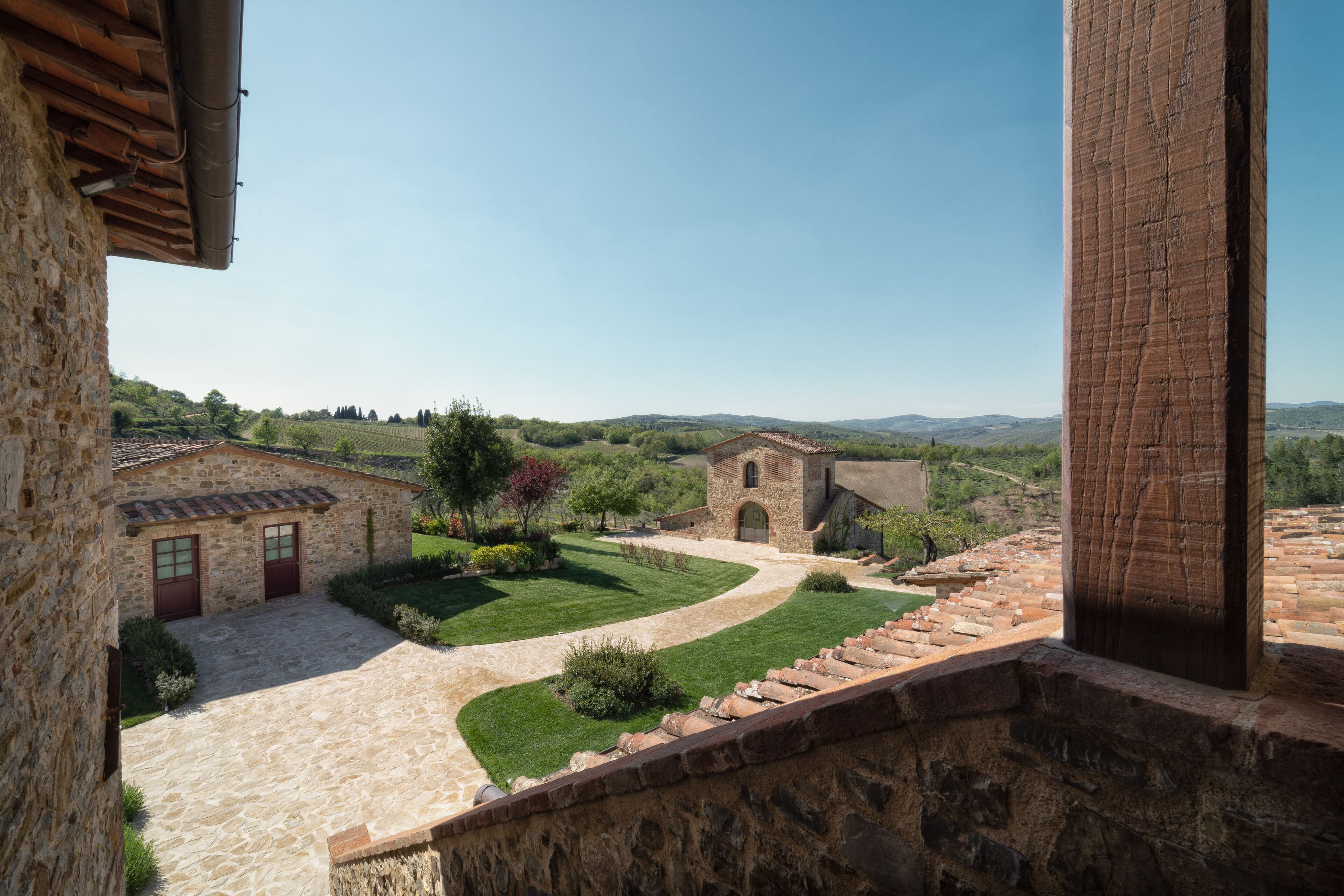Un edificio de piedra con un patio interior, un sendero de piedra y vistas del paisaje circundante.