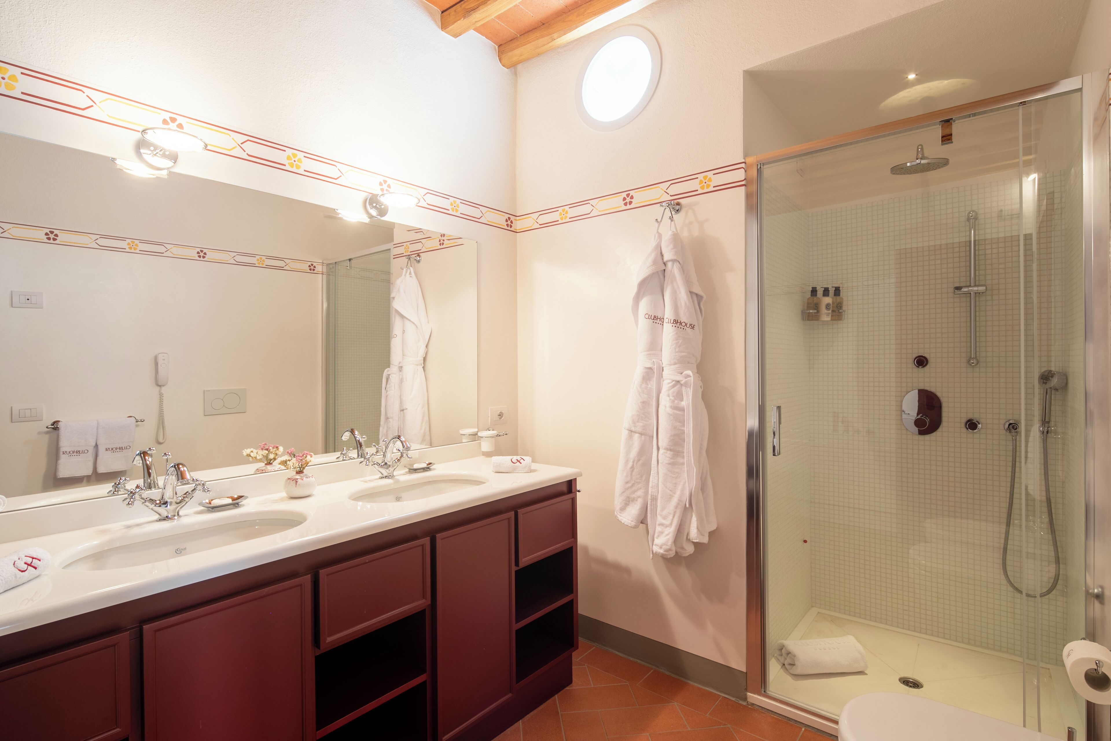 Un baño de hotel con un espejo grande, dos lavamanos, una ducha y un inodoro.