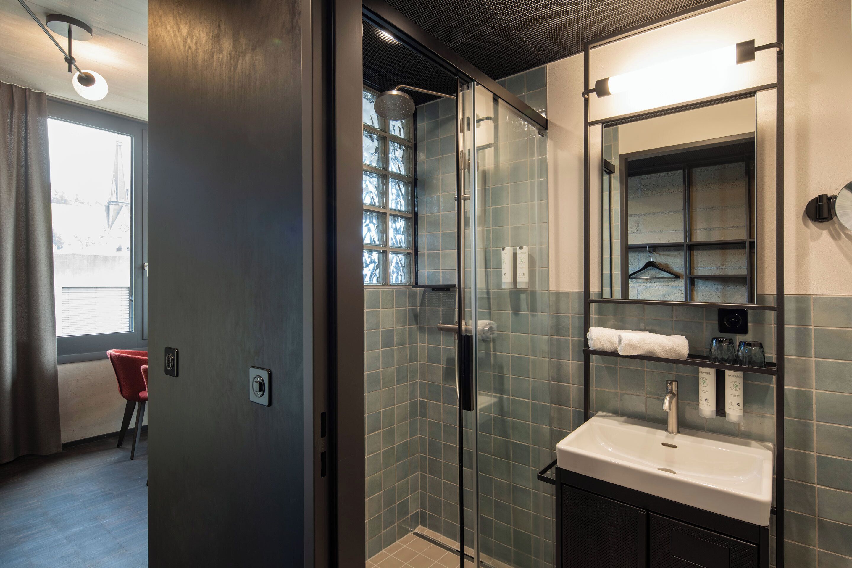 A modern bathroom with a glass-enclosed shower, a sink with a mirror above it, and a towel rack.