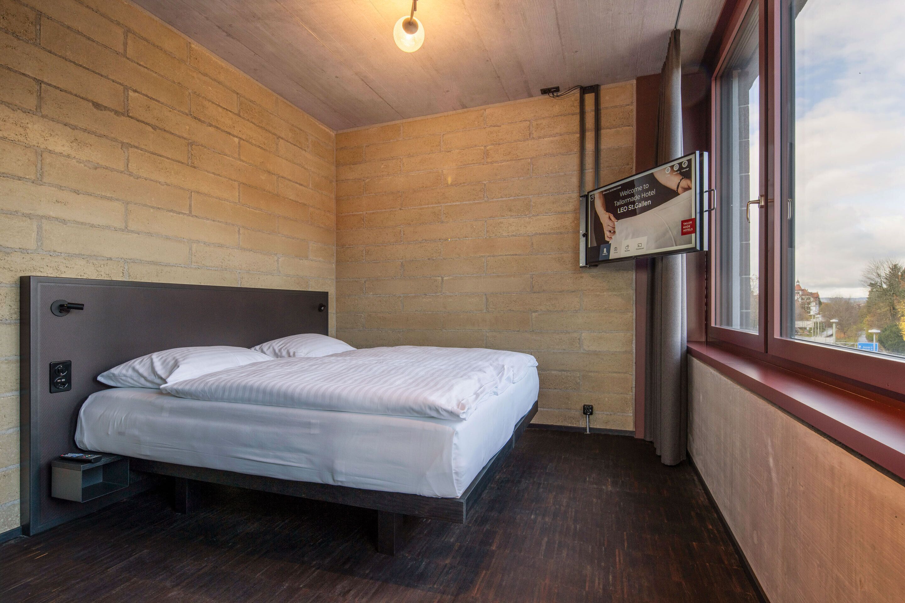 Een hotelkamer met een bed, houten wanden, een raam en een bord aan de muur.