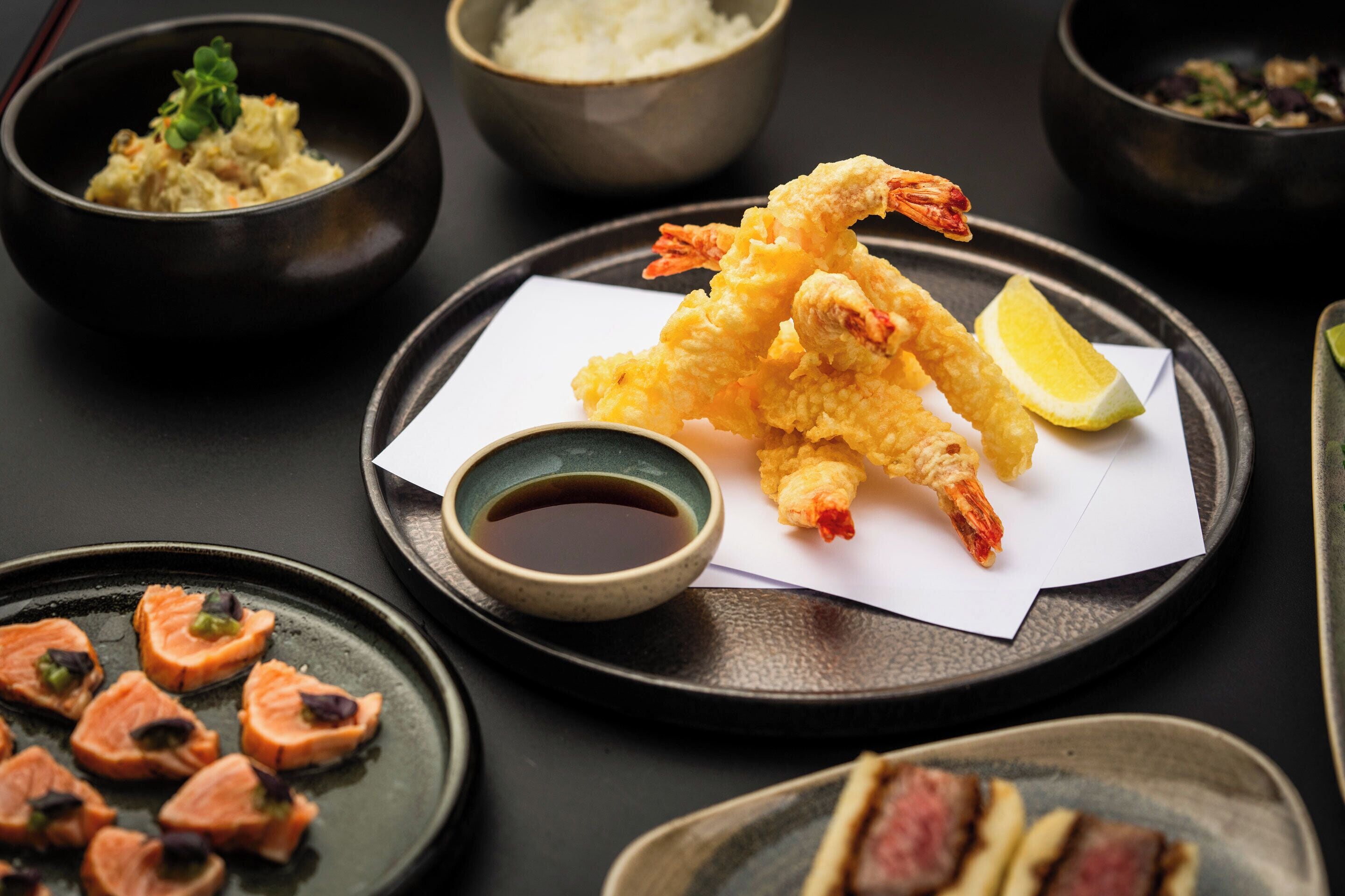 A variety of Japanese dishes including tempura shrimp, salmon, and rice bowls.