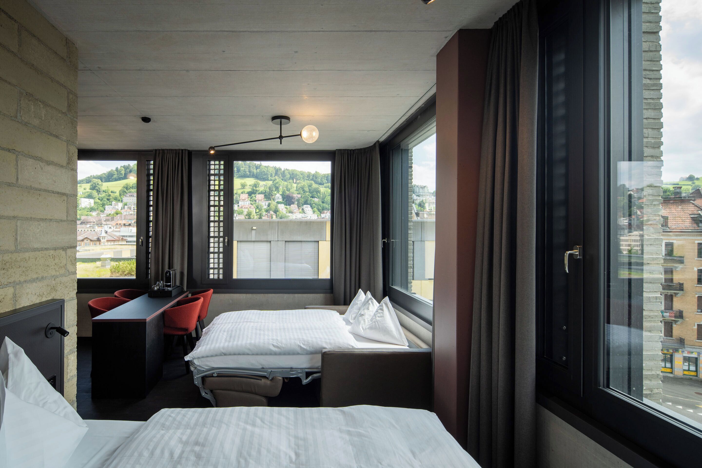 Quarto de hotel com duas camas, uma escrivaninha e vista para a paisagem urbana.