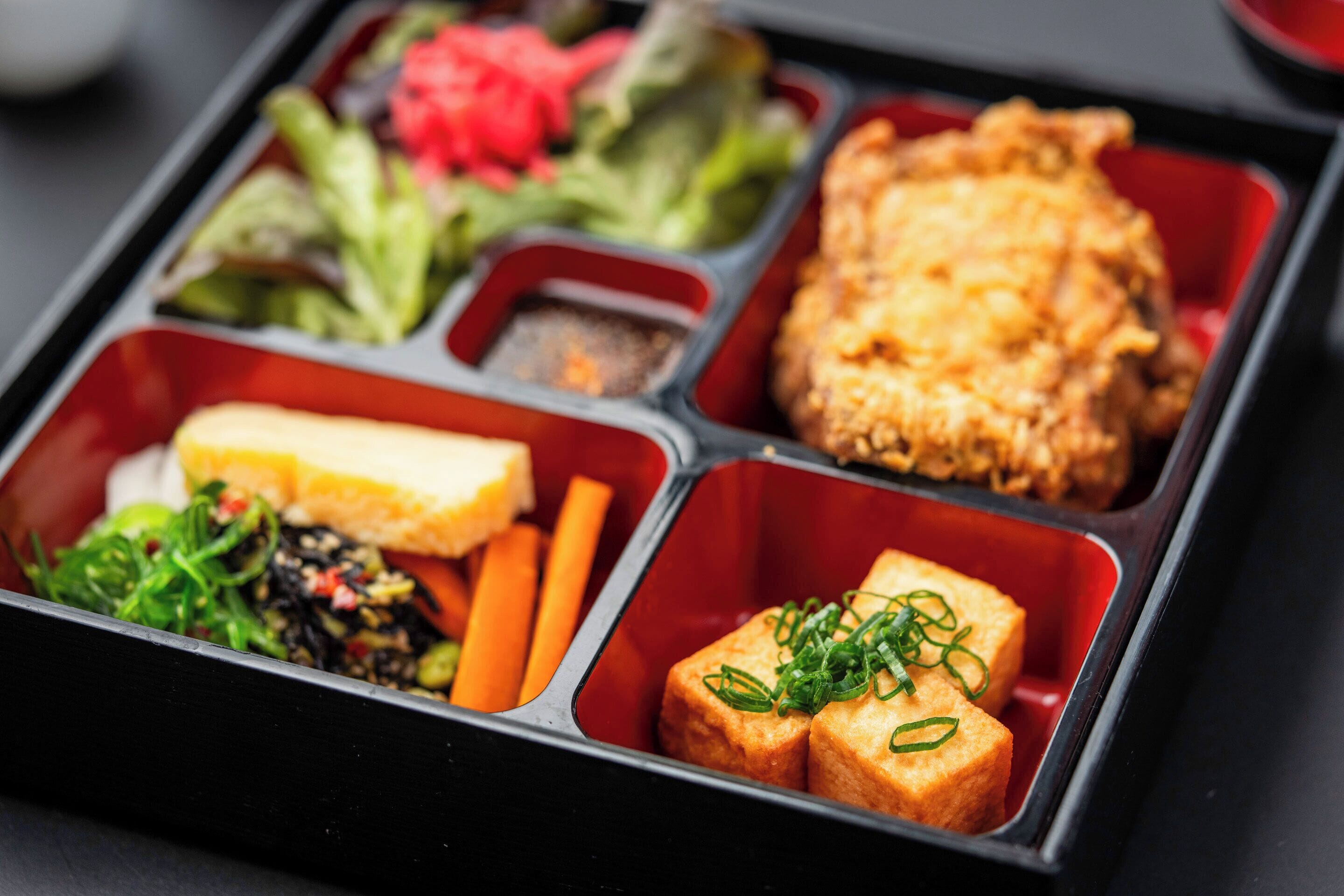A meal with various dishes in a compartmentalized tray.