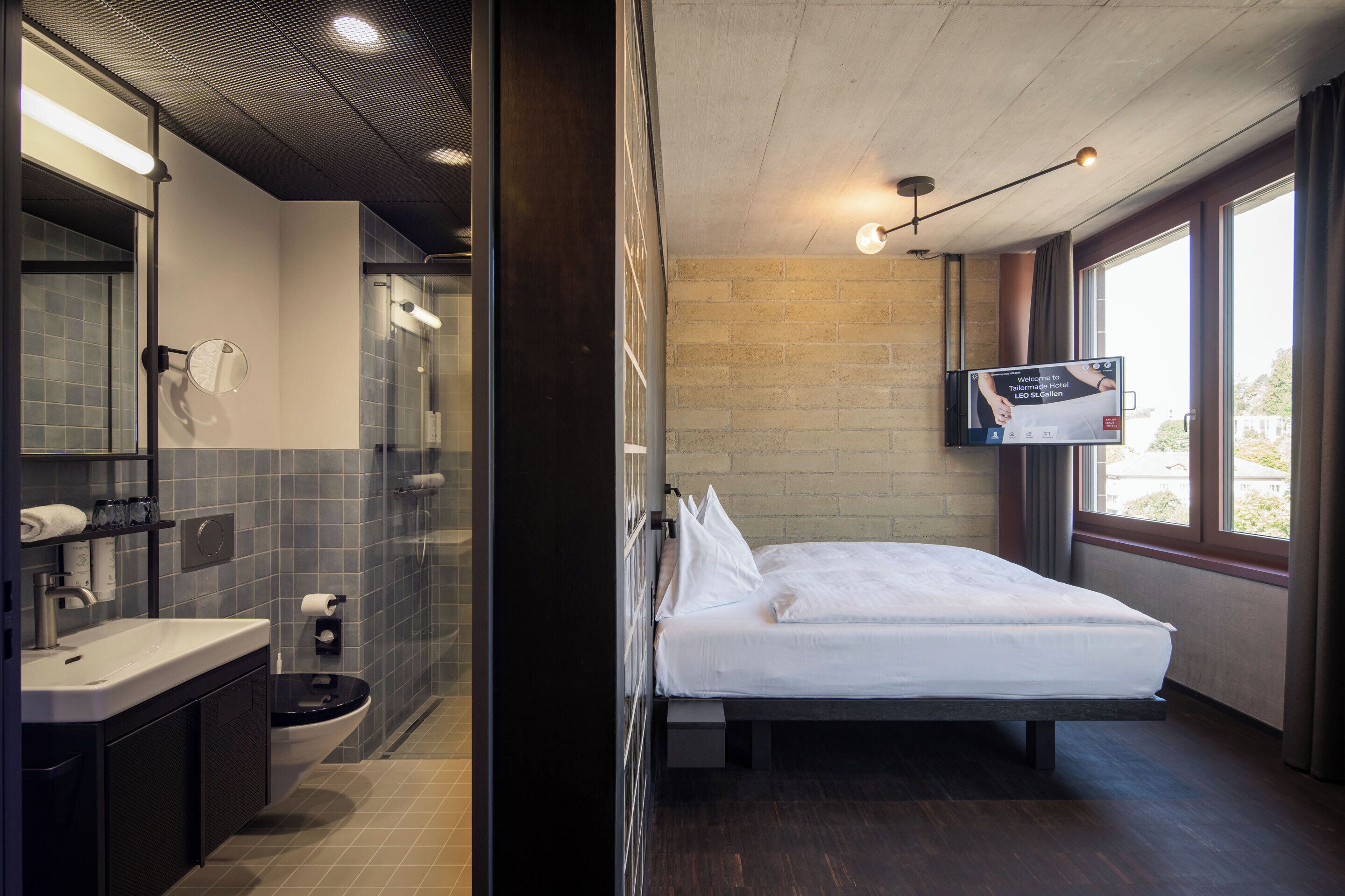 Une chambre d’hôtel moderne dotée d’un grand lit, d’une salle de bain avec douche et d’un téléviseur fixé au mur.