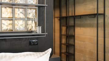 Una habitación moderna con una cama, un estante con paneles de vidrio decorativos y una pared de ladrillo.