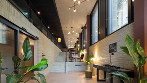 A modern interior with a staircase, seating area, and a 'Self Check In' sign.