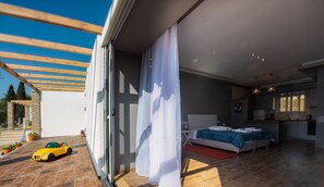 A modern bedroom with a bed, a desk, and a view of the outside.