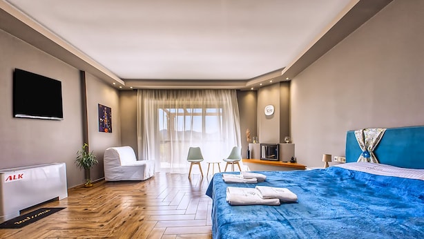 Ein modernes Hotelzimmer mit einem großen Bett, einem Schreibtisch, einem Sessel und einem Fernseher.