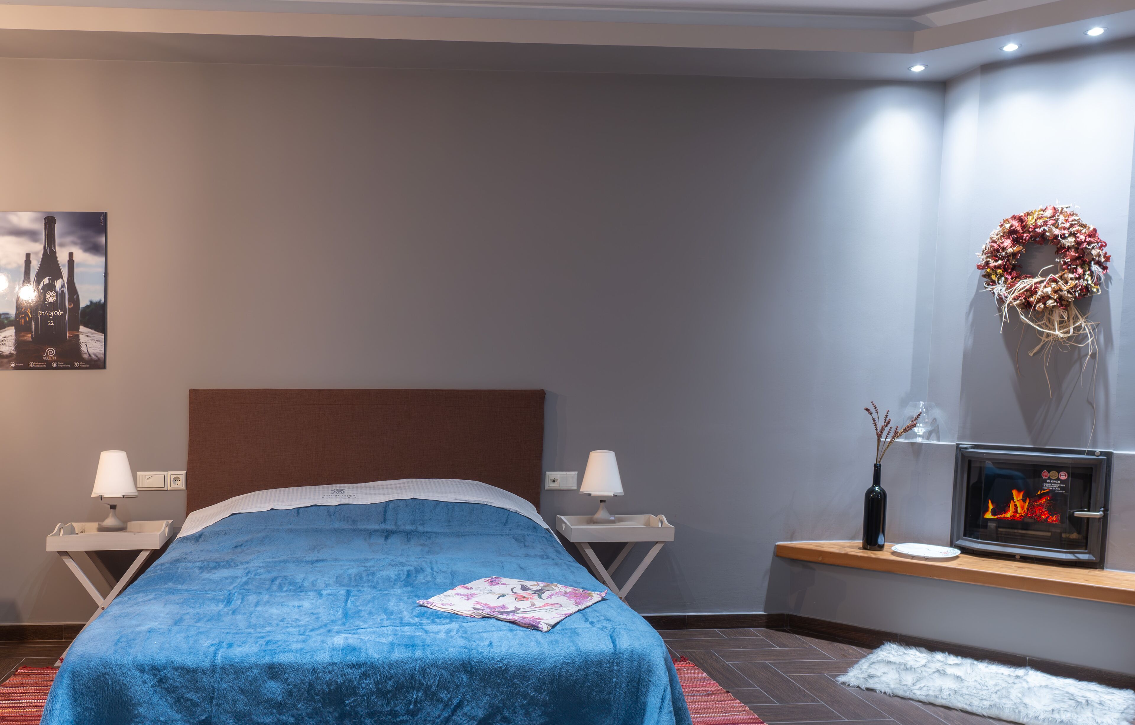 Un dormitorio con cama, mesitas de noche, chimenea, televisor montado en la pared y una guirnalda decorativa.