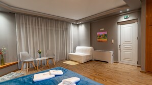 Ein Hotelzimmer mit einem Bett, zwei Stühlen, einem kleinen Tisch, einem Gemälde und einer Tür.