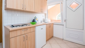 Una cocina con armarios de madera, un lavavajillas blanco y una ventana con vistas.