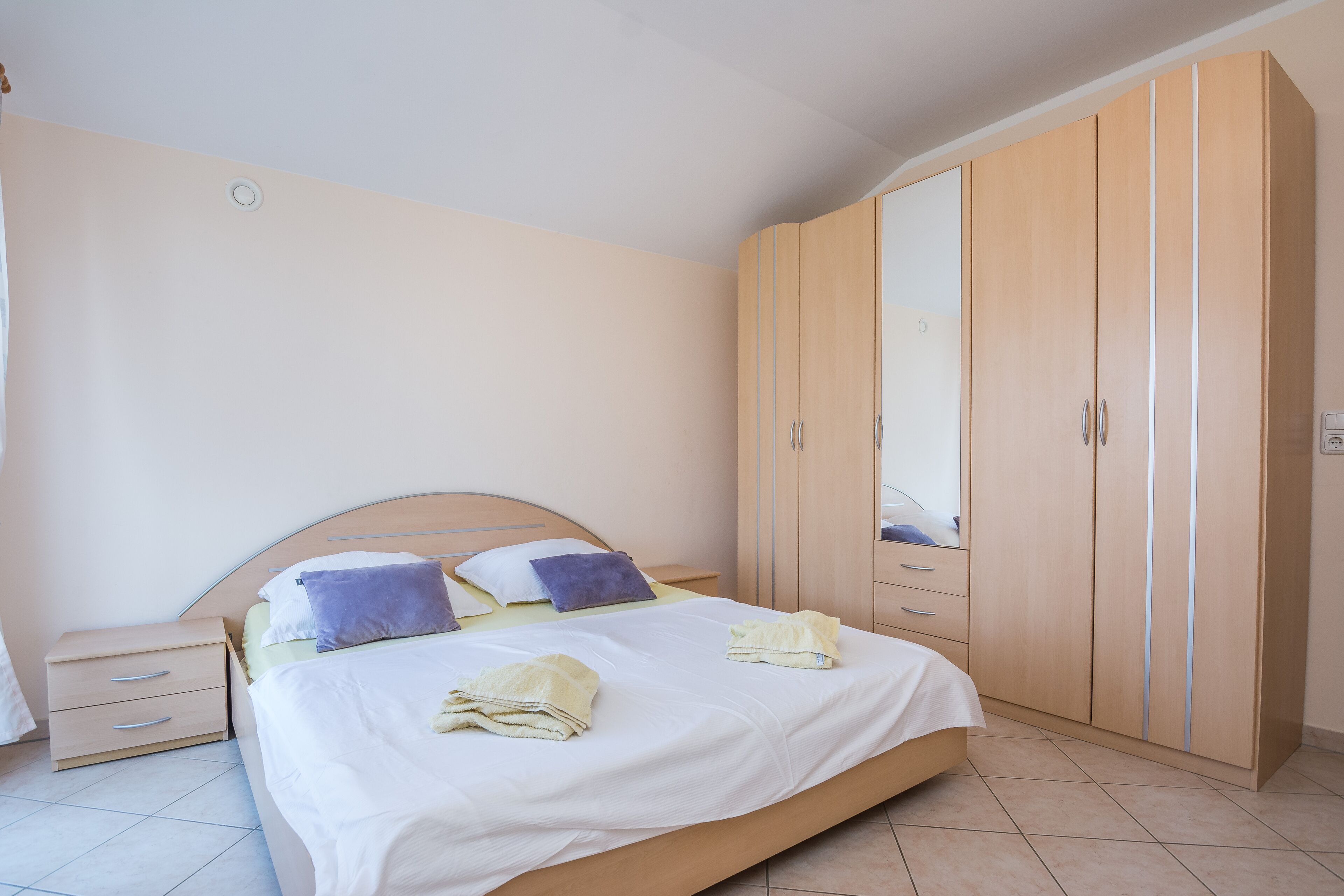 Een slaapkamer met een bed, nachtkastjes, een kledingkast en een spiegel.