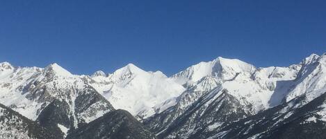 A mountain range with snow-covered peaks and a clear blue sky.