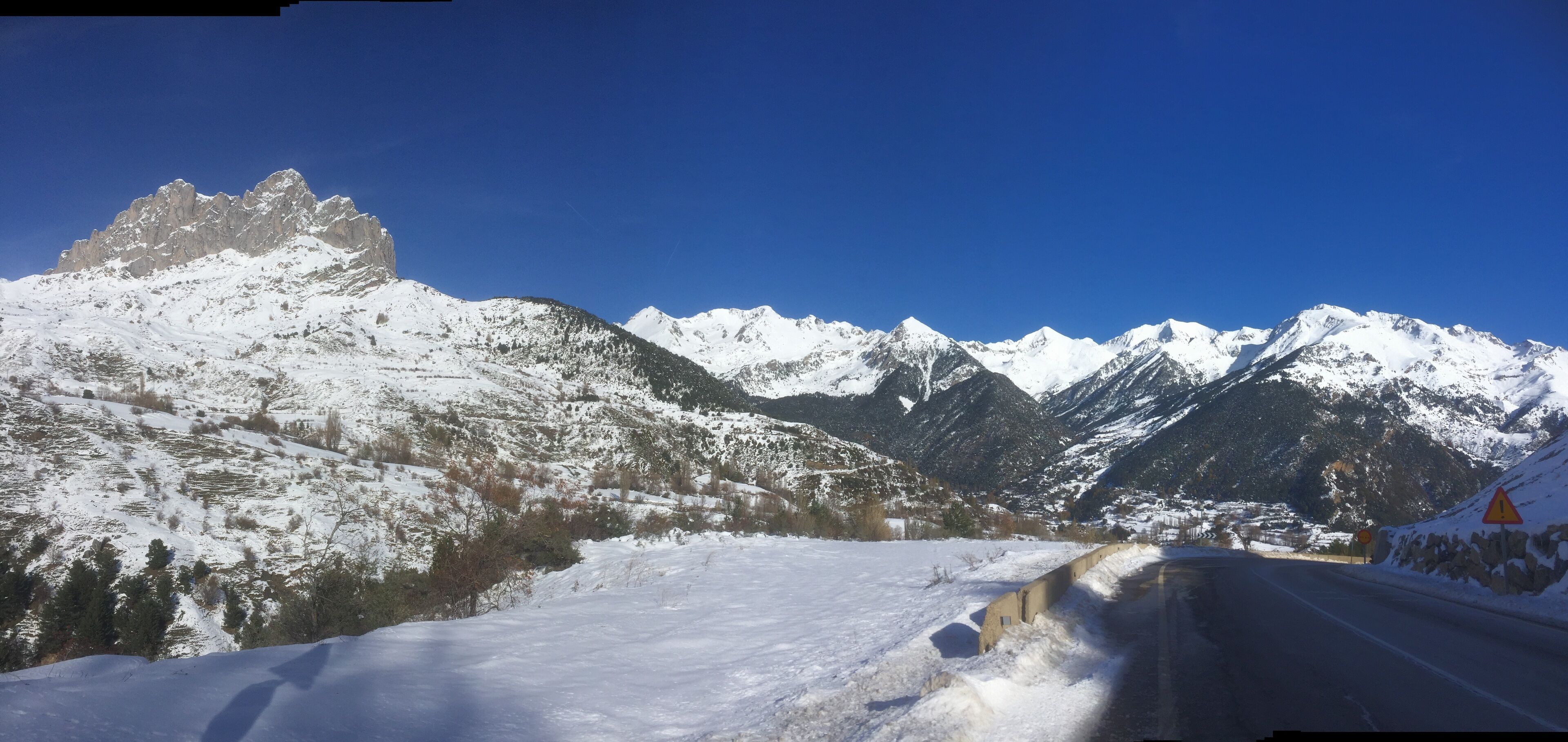 Una carretera nevada que serpentea por la montaña, bajo un cielo despejado.