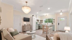 A modern living room with a sofa, coffee table, and a chandelier. - Seagrove Cottage- 4 Bikes Free! (Santa Rosa Beach)