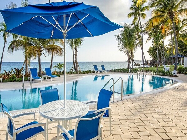 Relax by the ocean with a clear view, surrounded by palm trees and lounge chairs.