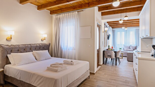 A bedroom with a large bed, a desk, and a kitchenette. - Casa Del Balsamo (Rethymno)