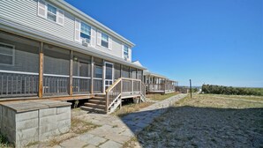 A coastal house with a covered porch, a stone pathway, and a view of the sea.