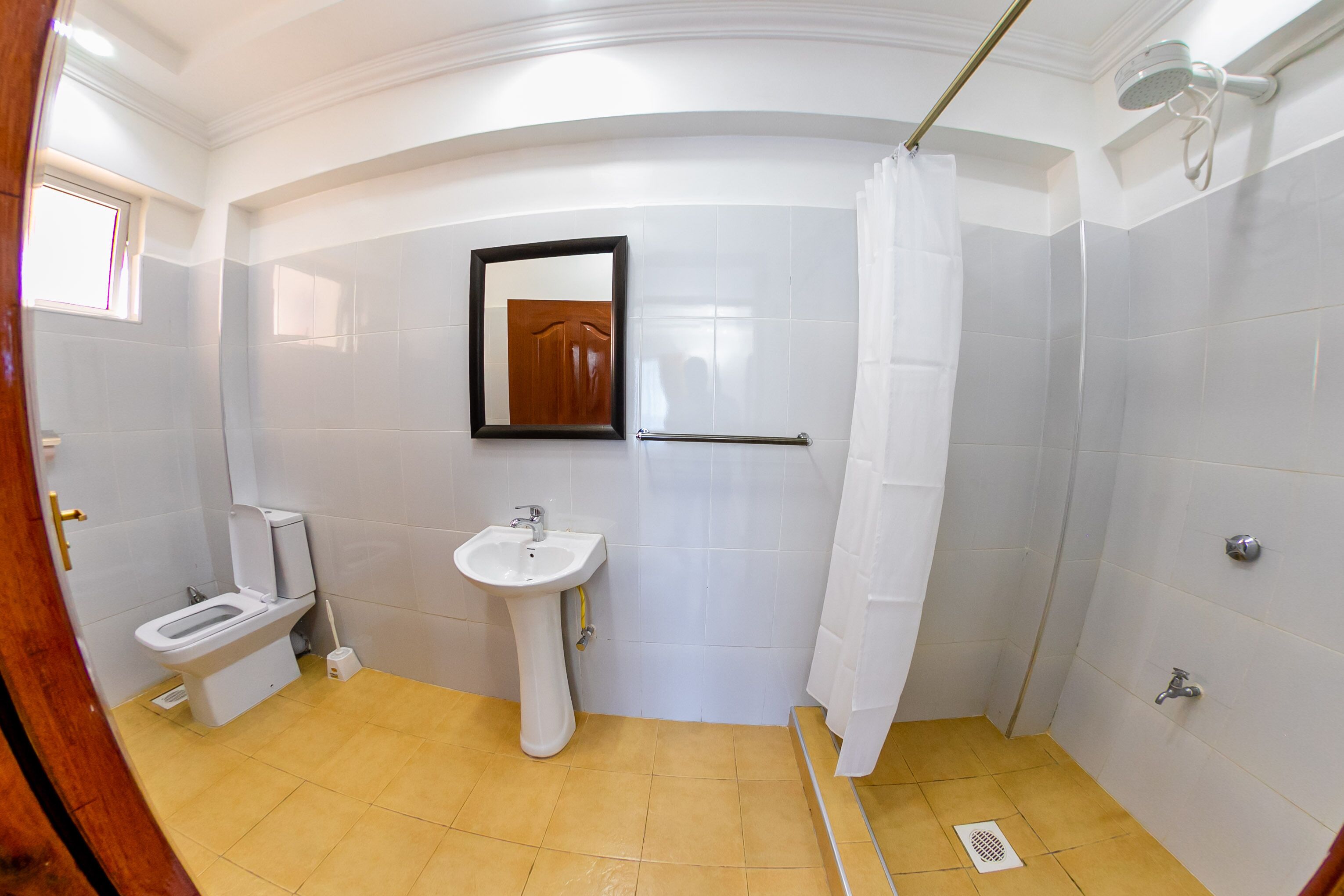 A bathroom with a toilet, sink, shower, and a mirror.
