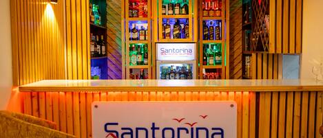 A bar area with wooden paneling and a sign for Santorina Home Suites.