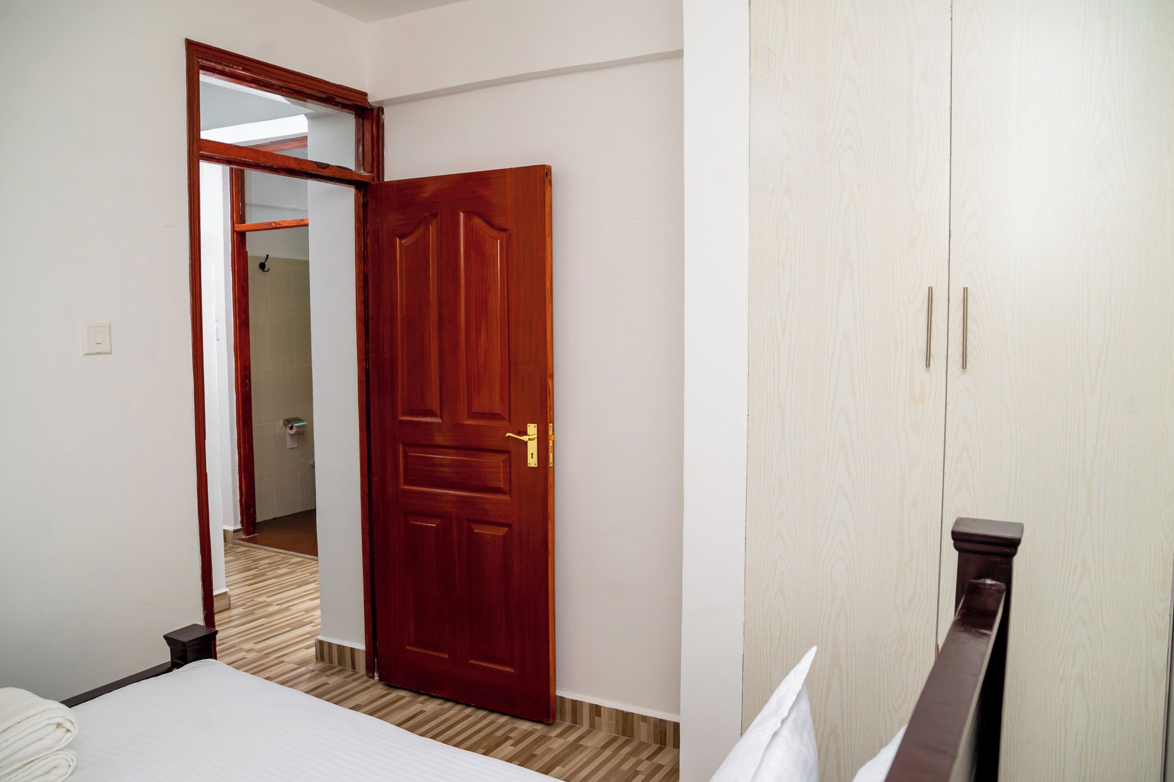 Una habitación de hotel con puerta de madera, una cama y un armario.