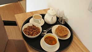 A tray with a cup of coffee, a bowl of chocolate, a plate of flatbread, and a bowl of soup on a wooden table.