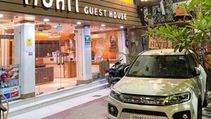 A building with a sign reading "MOHIT GUEST HOUSE" and a parked car in front.