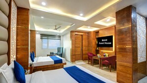 A hotel room with two beds, a desk, a chair, a TV, and a wardrobe.