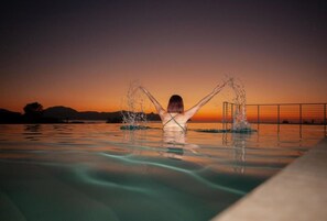 Eine Person in einem Schwimmbecken mit erhobenen Armen, Wasser spritzt umher.
