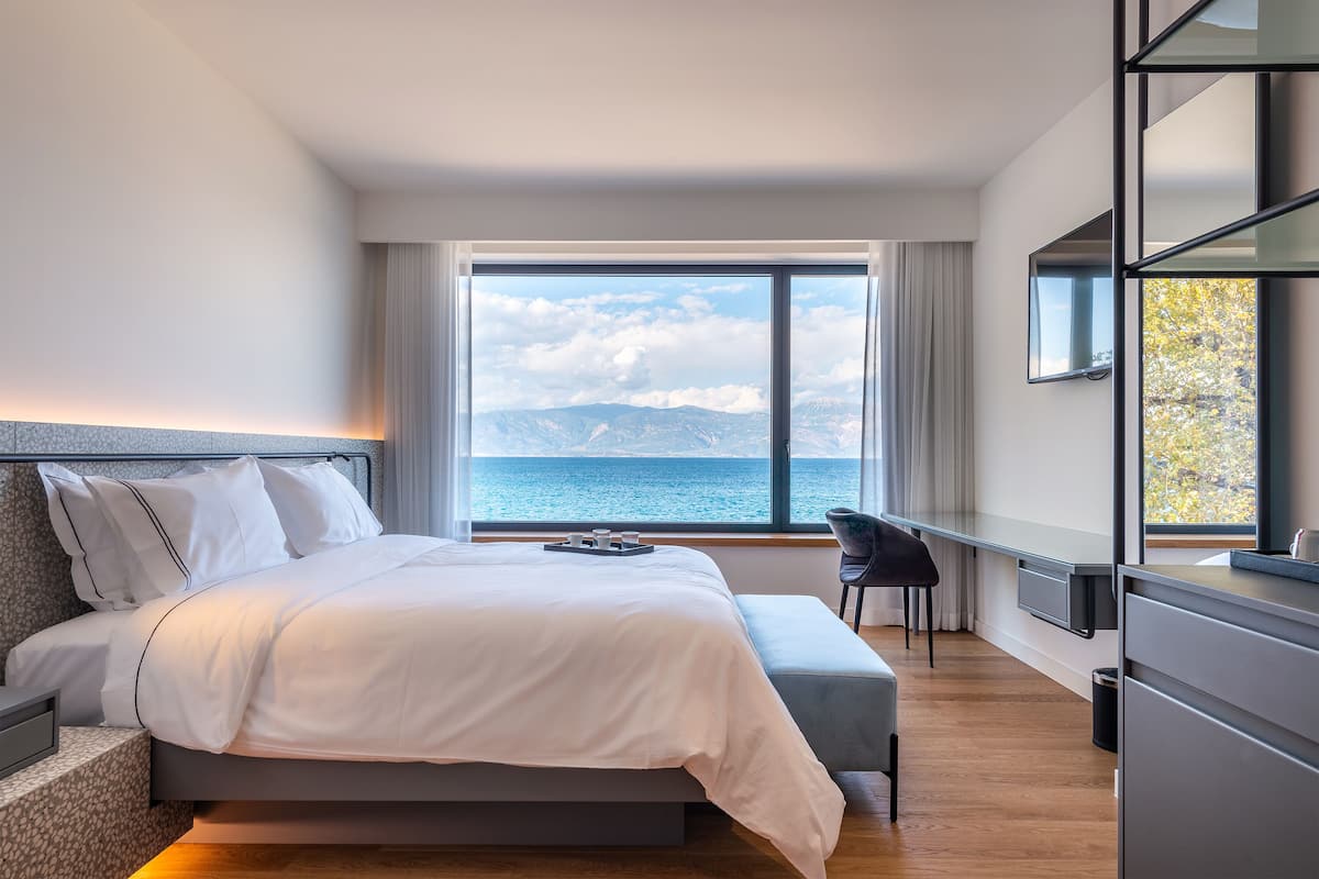 Un dormitorio moderno con una cama grande, un escritorio y vista al mar.
