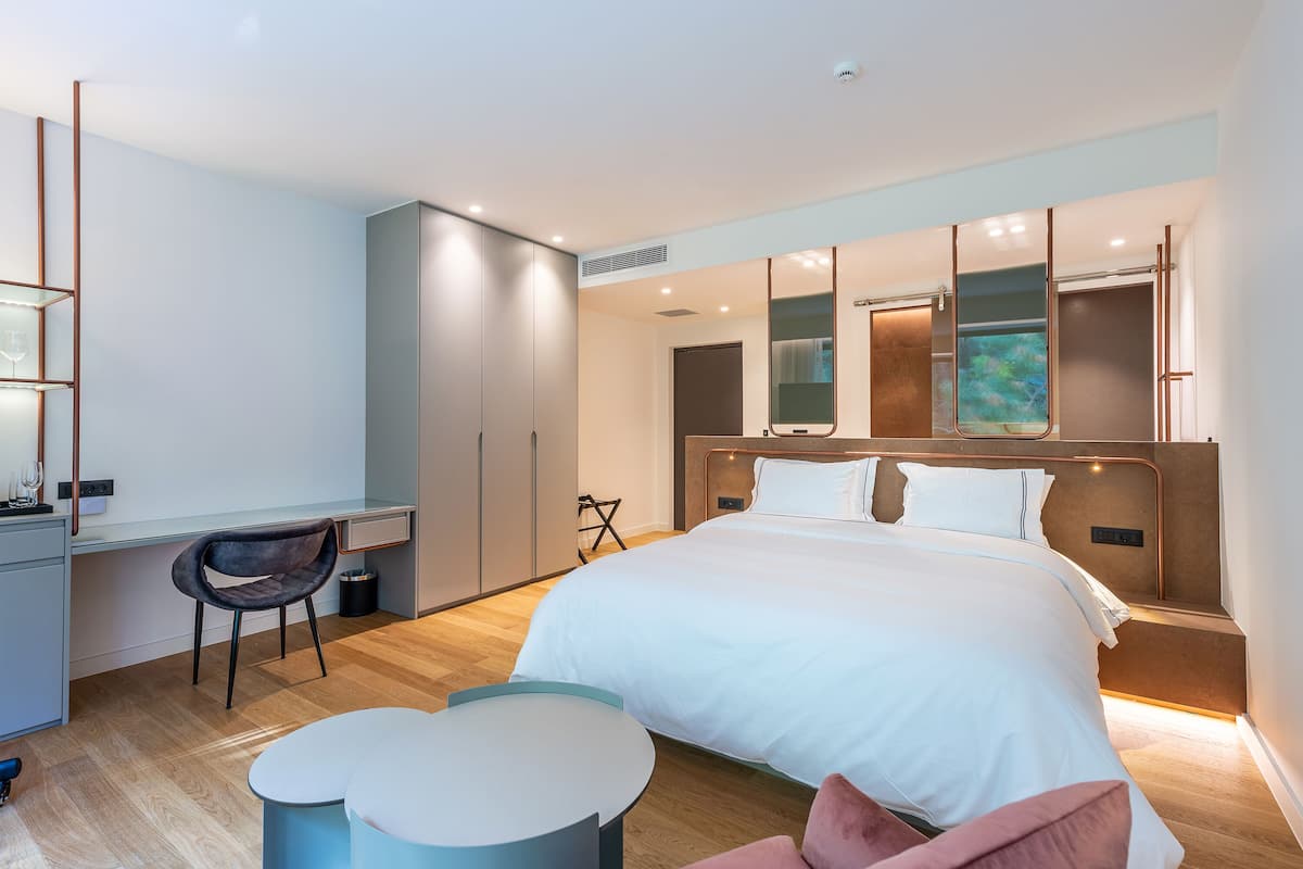 Una habitación de hotel moderna con una cama grande, un escritorio y una silla.