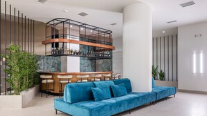 A modern bar area with a mezzanine, a blue sofa, and bar stools. - Amario Suites Hotel (Aigialeia)