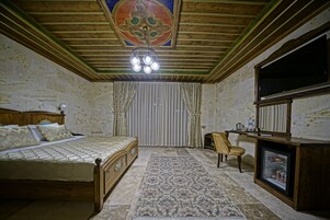 Quarto com cama, cadeira, televisão e um pequeno frigorífico.
