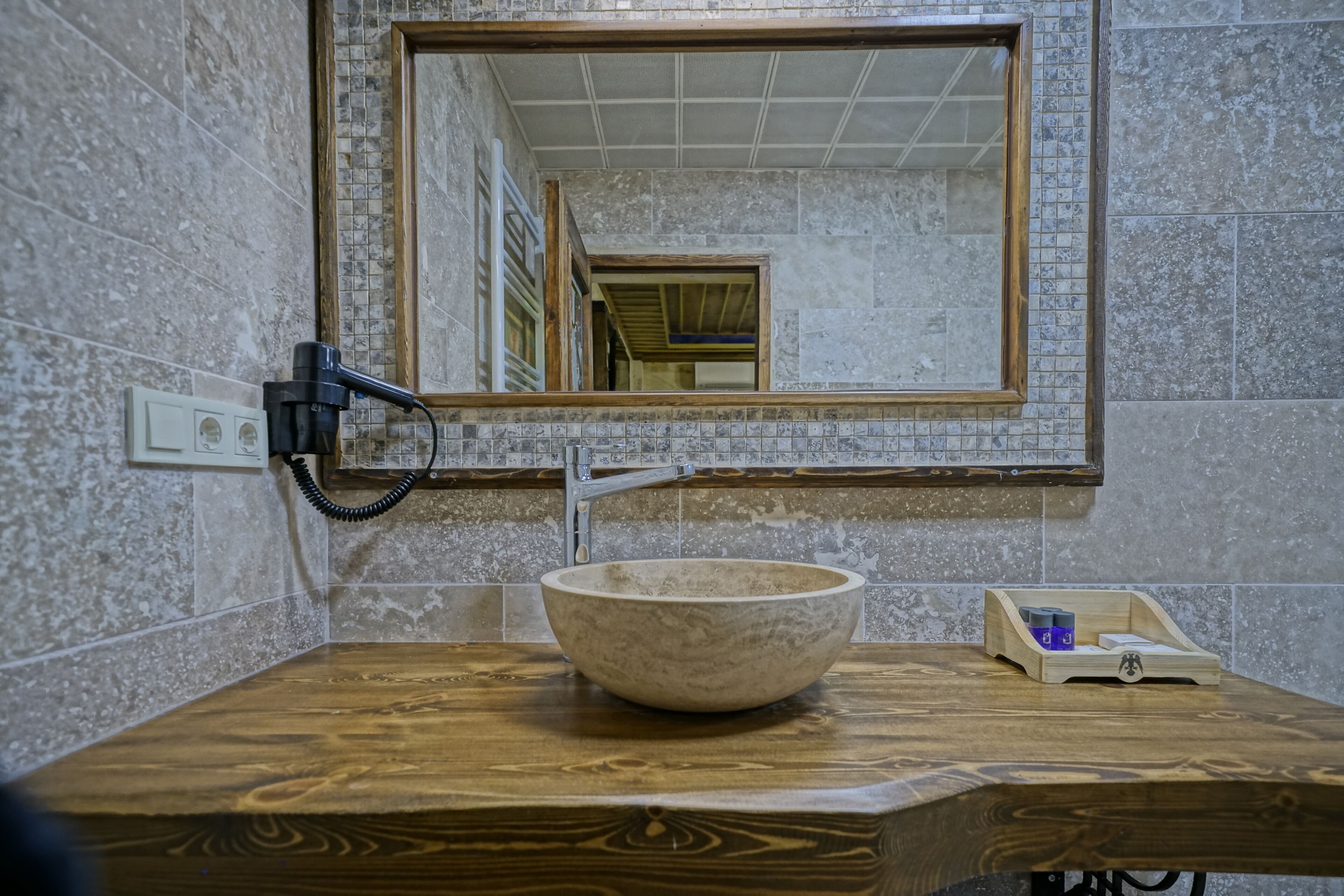Une salle de bain avec un meuble-lavabo en bois, un lavabo en marbre, un miroir et un porte-serviettes.