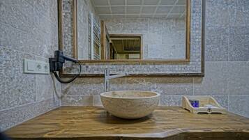 Une salle de bain avec un meuble-lavabo en bois, un lavabo en marbre, un miroir et un porte-serviettes.