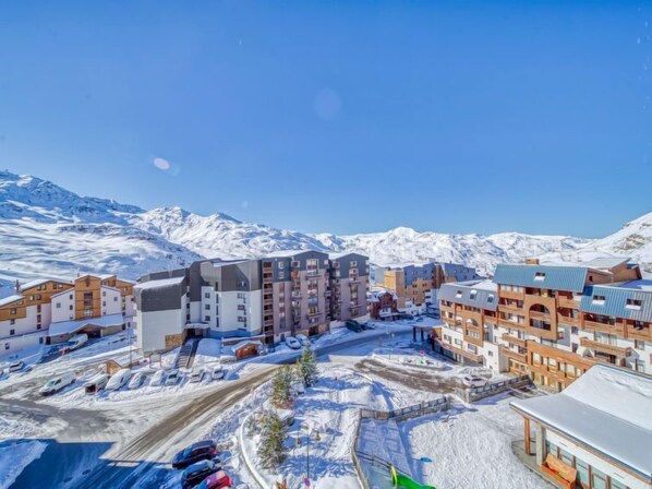 Une ville enneigée, avec des bâtiments modernes et une chaîne de montagnes en arrière-plan.