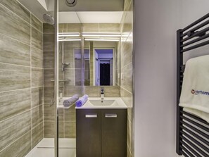 Une salle de bain moderne avec une douche à parois de verre, un lavabo avec une serviette et un miroir.