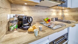 Een moderne keuken met houten kastjes, een ingebouwde koffiezetapparaat, een fruitschaal en een broodmand.