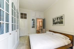 Features a large bed, wardrobe with mirror, and bathroom through an open door.