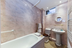 Enjoy a relaxing soak in the bathtub, paired with a pedestal sink and vanity.