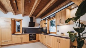 Una cocina moderna con armarios de madera, horno empotrado y un ventanal amplio.