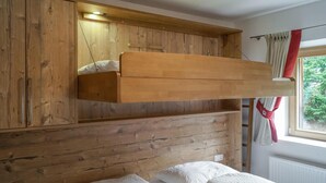 Un letto a castello con testiera in legno e una finestra con tende.