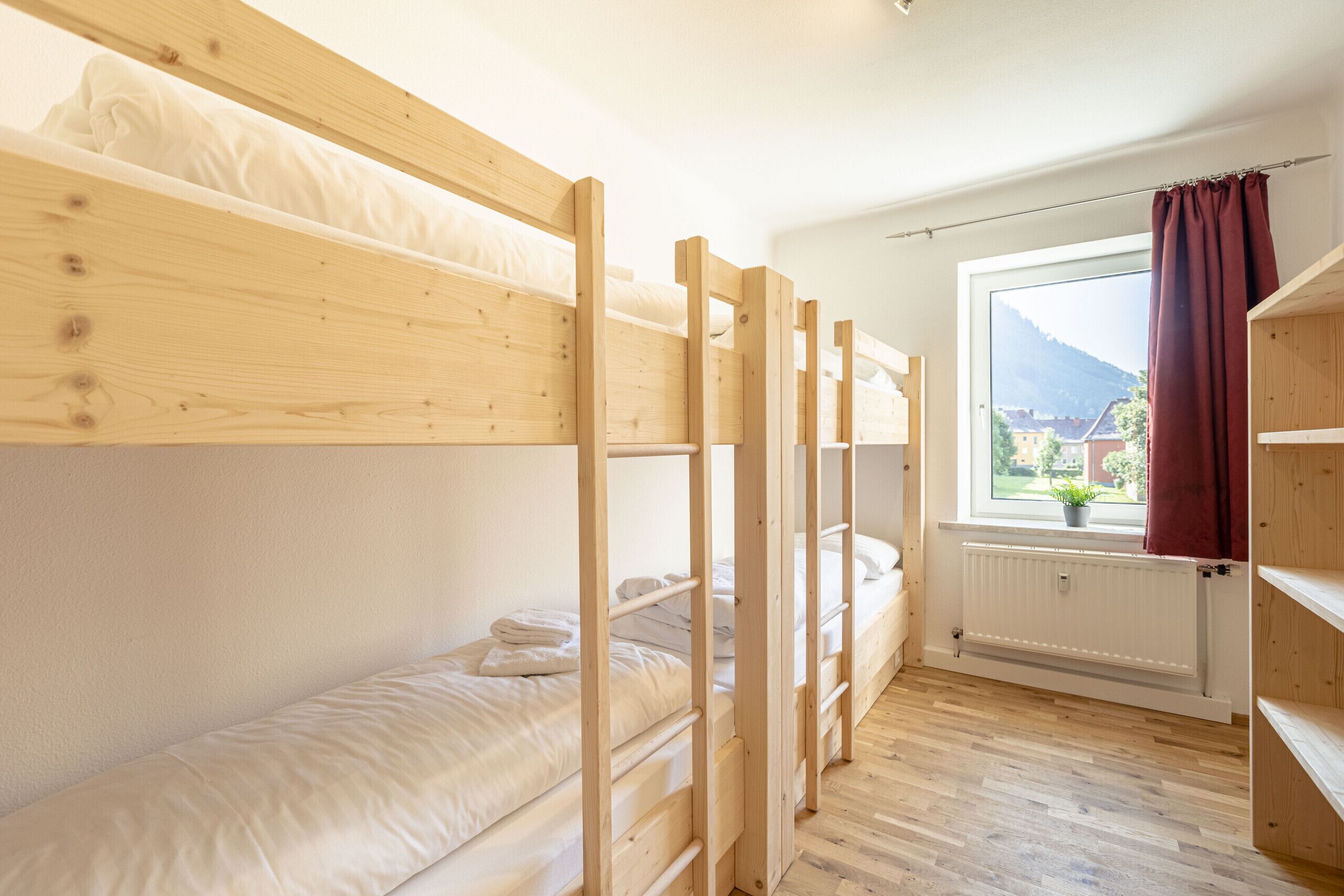 Une chambre avec un lit superposé, une fenêtre et un radiateur.