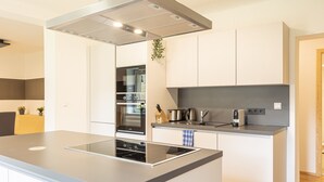 Een moderne keuken met een centraal eiland, een ingebouwde oven en roestvrijstalen apparatuur.