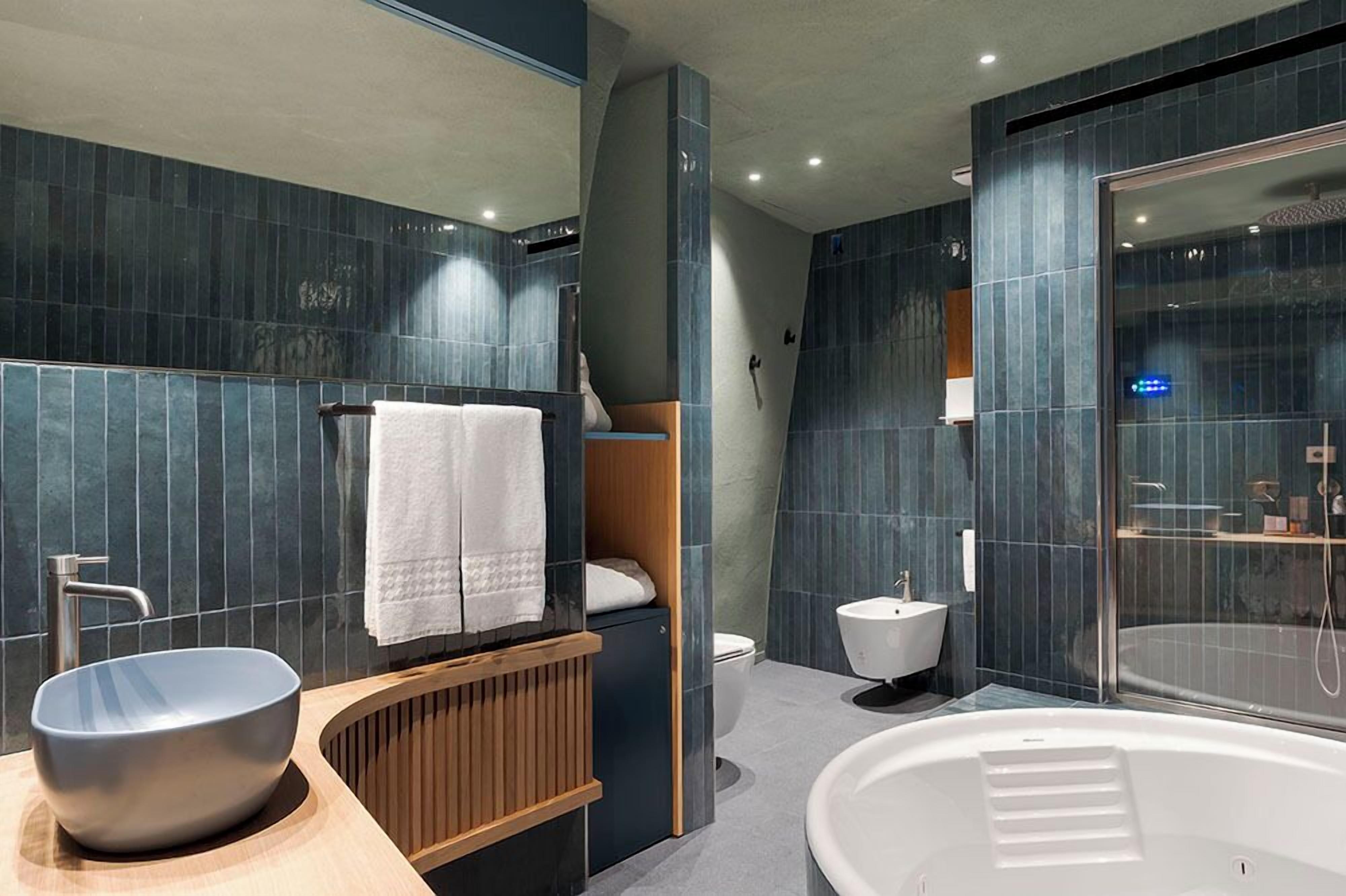 Un baño moderno con una bañera grande, un tocador de madera, un lavamanos y un inodoro.