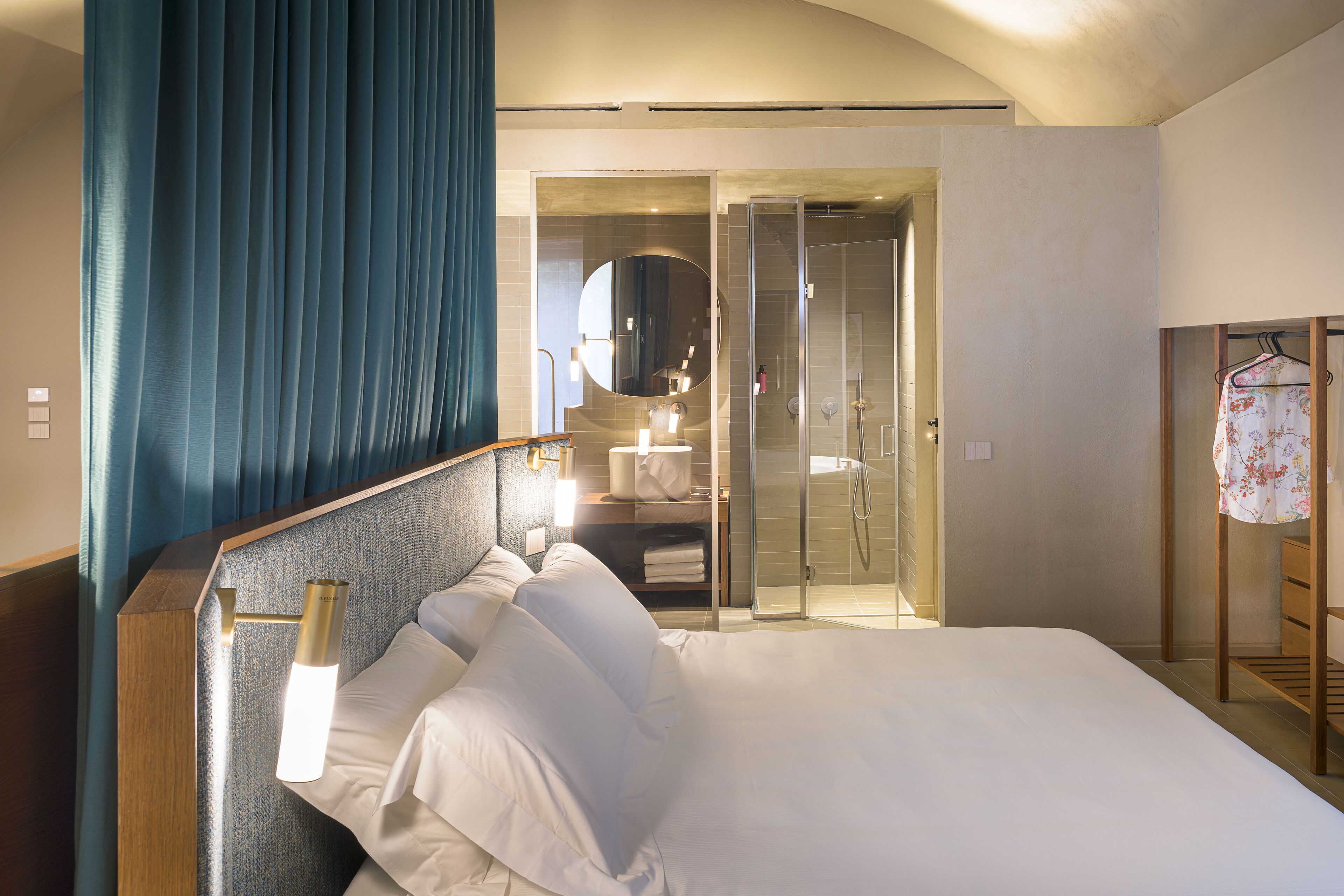 A hotel room with a large bed, a shower area, and a mirror.
